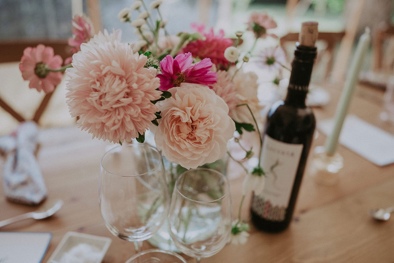 Beautiful pink flowers in vase with wine, candle and glasses