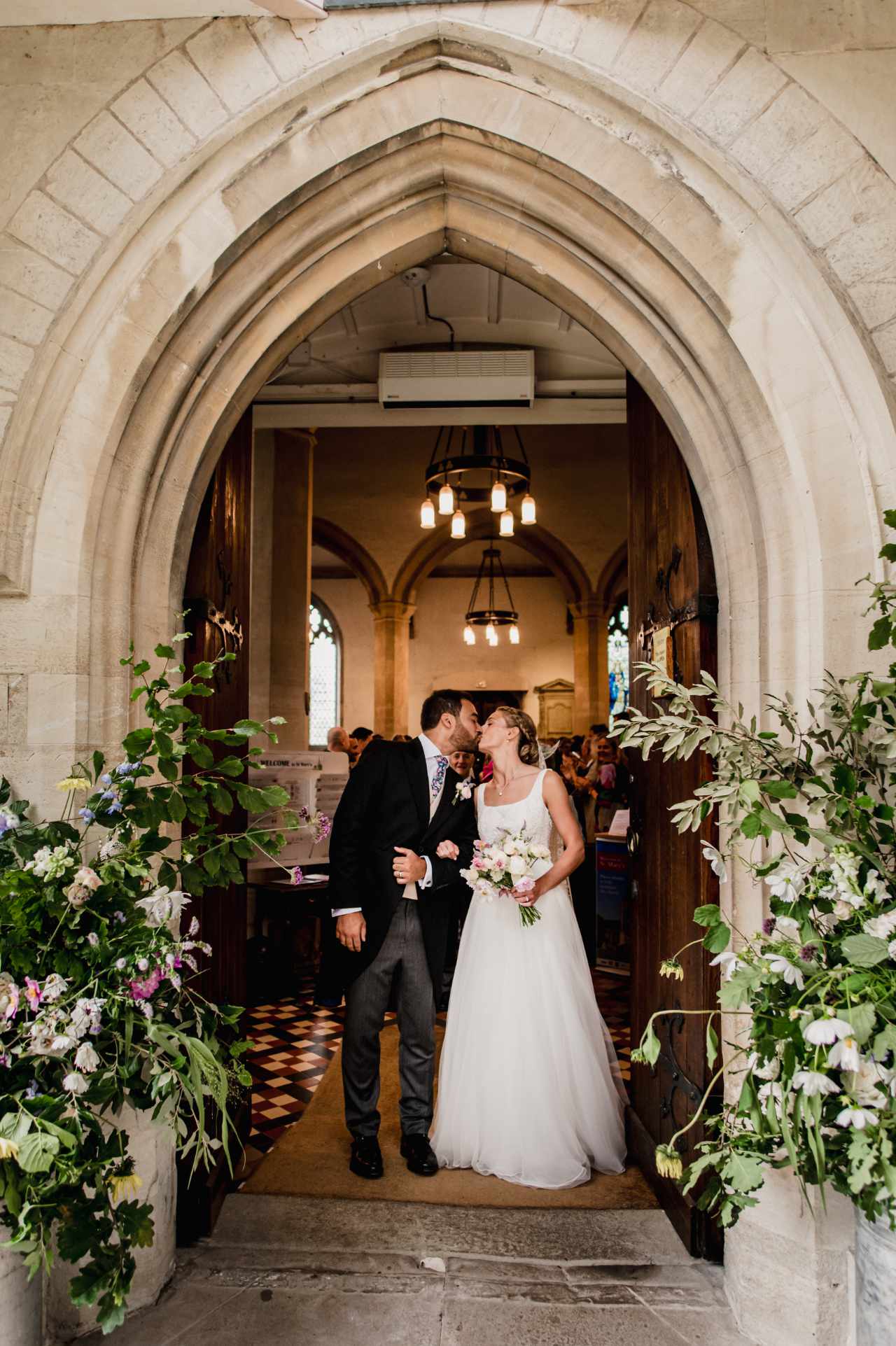 Bride and groom in church archway with flowers