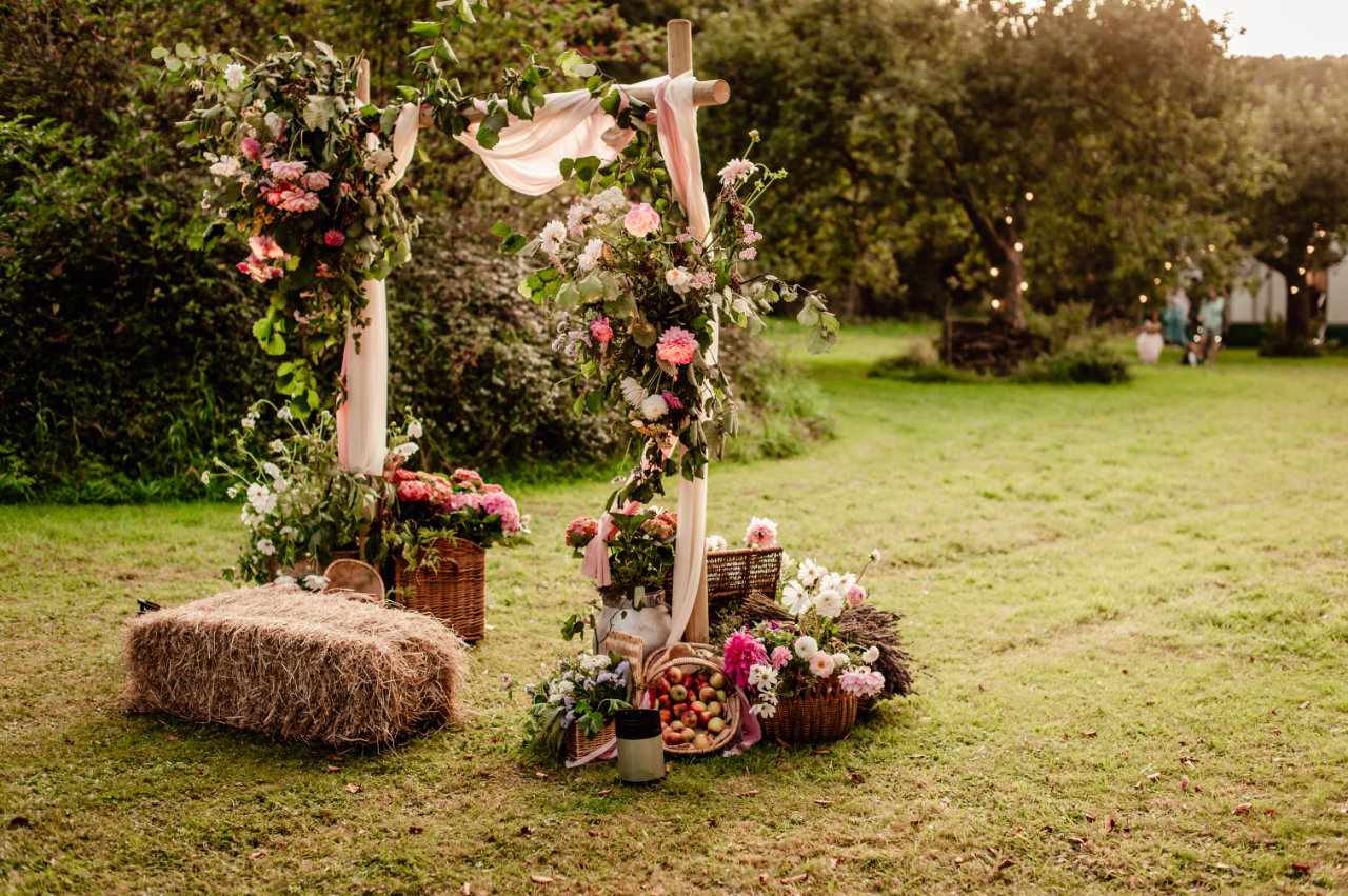 Countryside outdoor wedding with apples, flowers and hay bale surrounding rustic archway