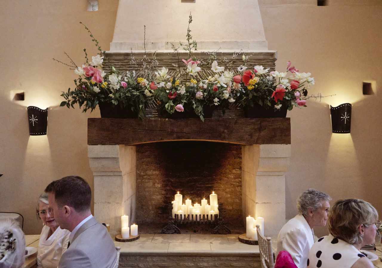Wedding flowers on a mantle above a fireplace with candles