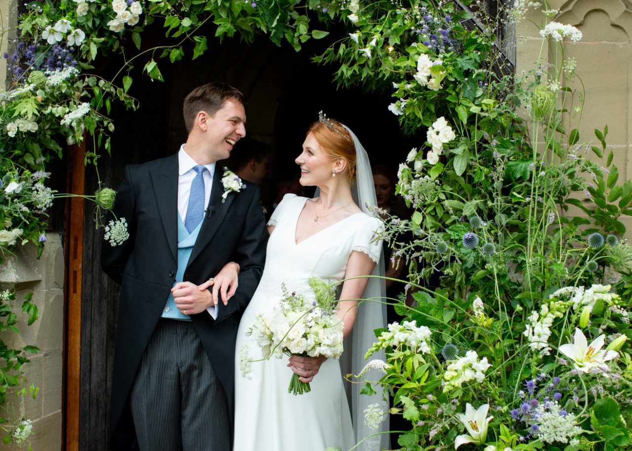 Happy smiling wedded couple under floral arch