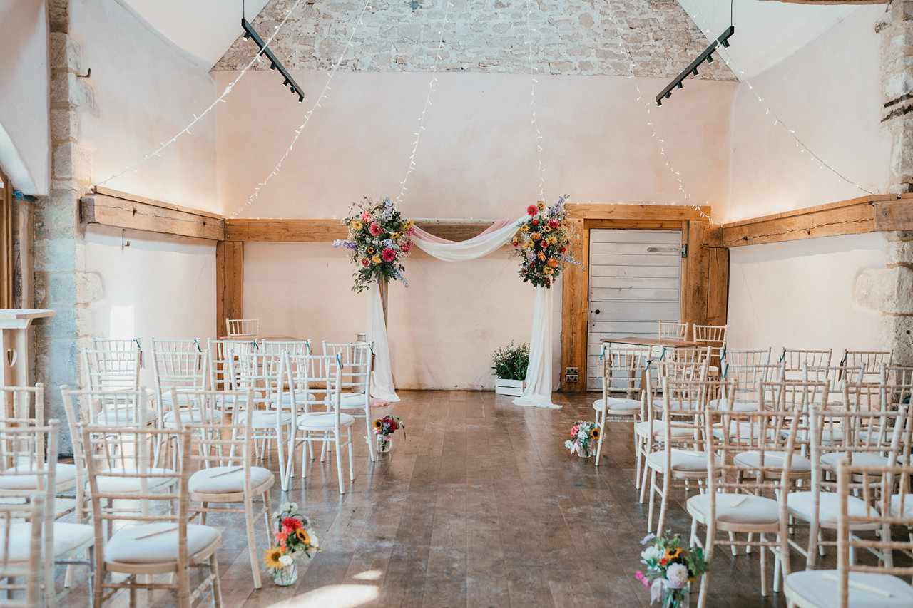 Barn wedding venue for ceremony with floral arch