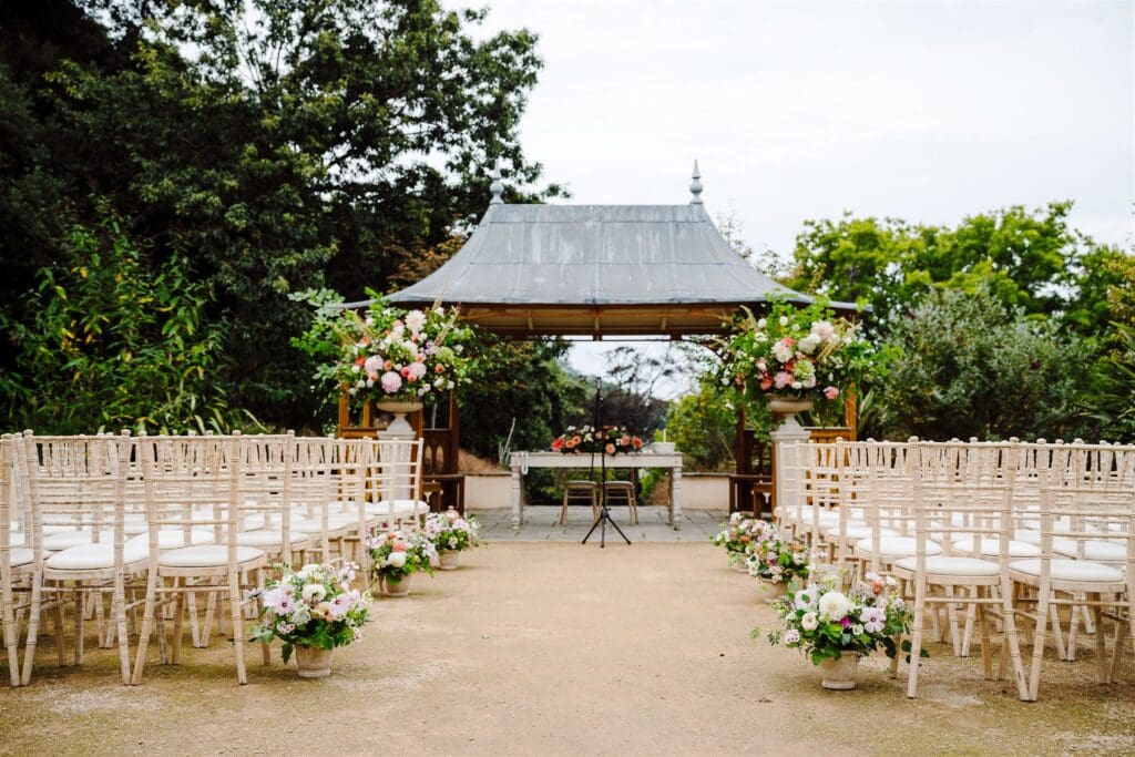 Outdoor Wedding Ceremony at Clevedon Hall with floral urns and aisle meadows